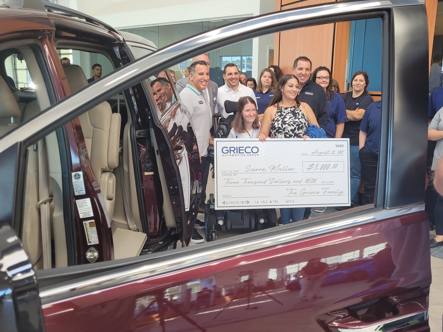 BIG CHECK: Seen through the drivers side window of the family’s new van, Robert Grieco, Pre-Owned Director and Grieco Auto Group Partner, presented Ciarra Muller with an oversized ceremonial check for $3,000 “for school supplies.” Her family joined her in the Grieco Honda showroom, where they also received a Honda Odyssey EX, fully equipped to accommodate Muller’s wheelchair.